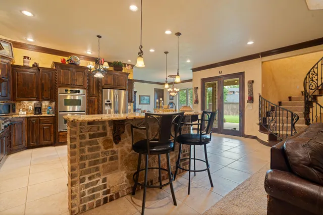 a dining hall with stainless steel appliances kitchen island granite countertop a dining table and chairs