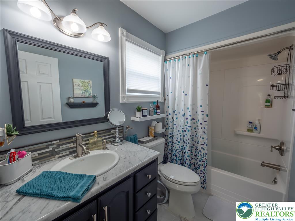 2087 Hopewell Road Bethlehem, PA 18017 - Photo 29 of 38 A well-appointed bathroom with a vanity, sink, mirror, toilet, and a bathtub with an overhead shower.