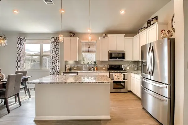 a kitchen with stainless steel appliances granite countertop a refrigerator a stove top oven a sink and a refrigerator