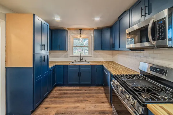 a kitchen with stainless steel appliances granite countertop a stove a sink and a microwave