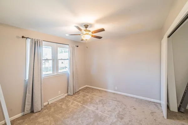 an empty room with windows and fan