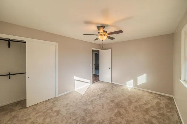a view of an empty room with a chandelier fan