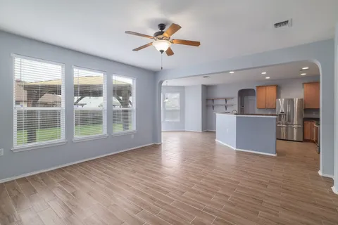 a view of an empty room with a window and wooden floor