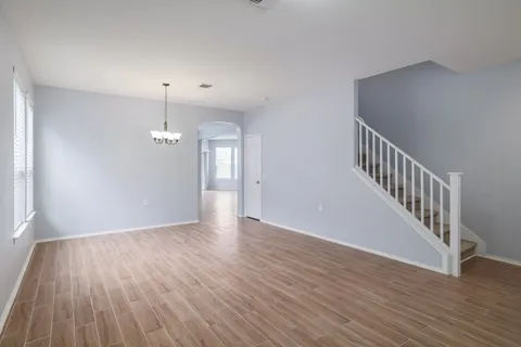 a view of an empty room with wooden floor and stairs