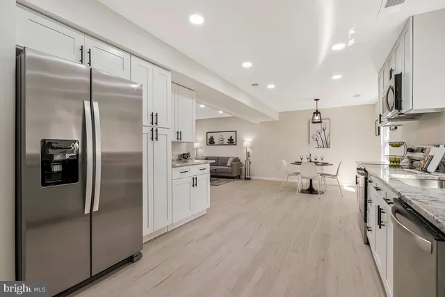 a kitchen with stainless steel appliances granite countertop a refrigerator a stove and a sink