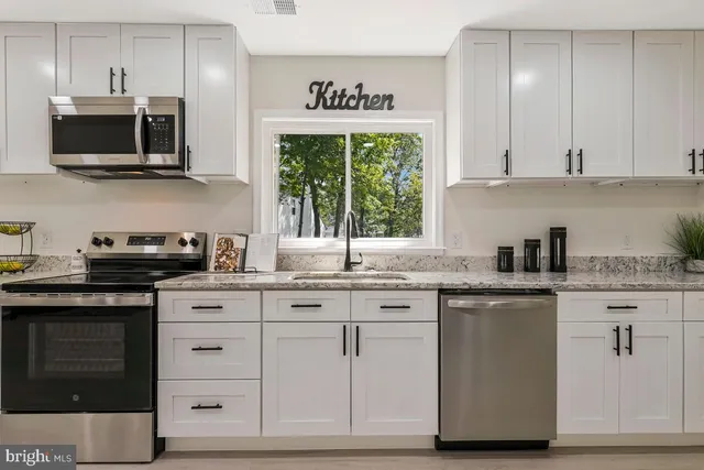 a kitchen with stainless steel appliances granite countertop a stove a sink and a microwave