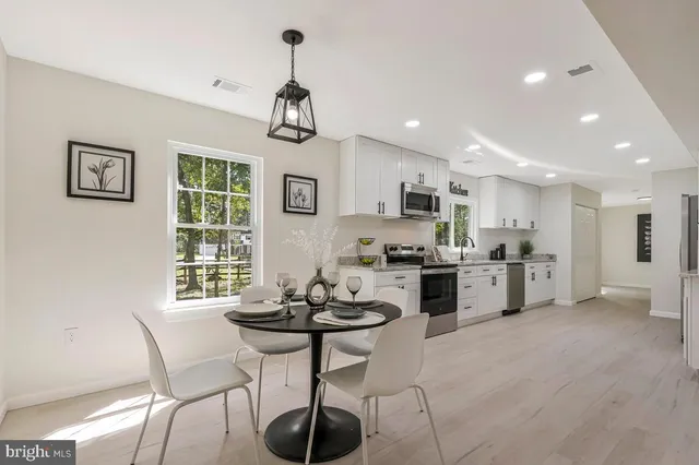 a kitchen with stainless steel appliances a table and chairs in it
