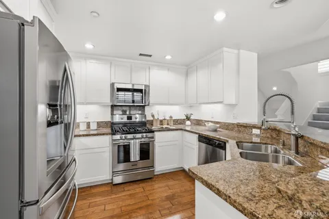 a kitchen with stainless steel appliances granite countertop a stove top oven a sink and a refrigerator