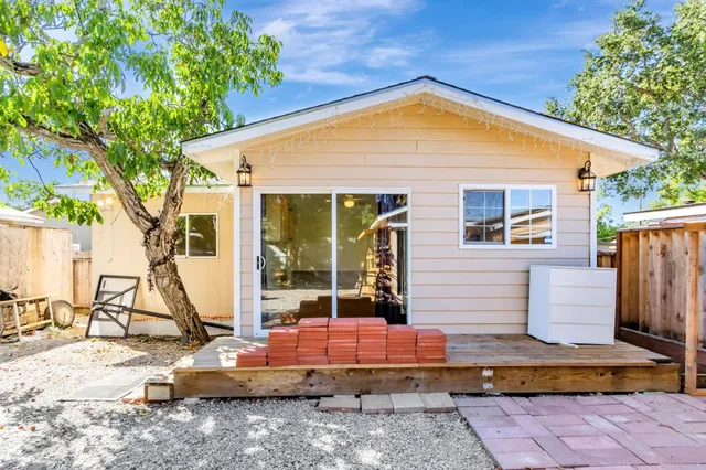 a view of an empty room with wooden floor and a kitchen