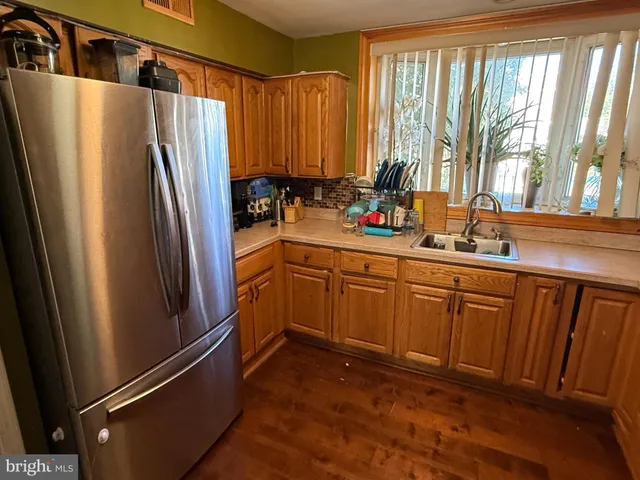 a kitchen with stainless steel appliances granite countertop wooden cabinets a sink a stove a refrigerator with grey cabinets and wooden floor