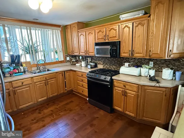 a kitchen with stainless steel appliances granite countertop sink stove refrigerator and a window