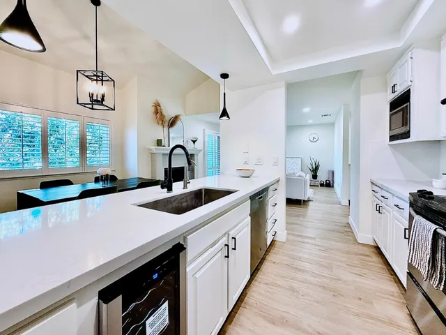 a large kitchen with stainless steel appliances a sink dishwasher a stove a refrigerator and a dining table with wooden floor