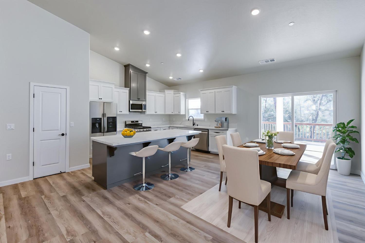 41940 Colt Court Coarsegold, CA 93614 - Photo 11 of 50 a kitchen with a dining table chairs and white cabinets