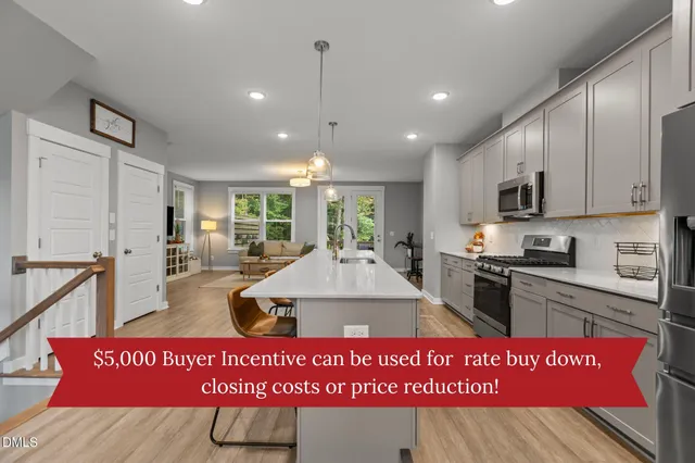 a view of kitchen with stainless steel appliances granite countertop a stove a sink dishwasher a refrigerator white cabinets and wooden floor
