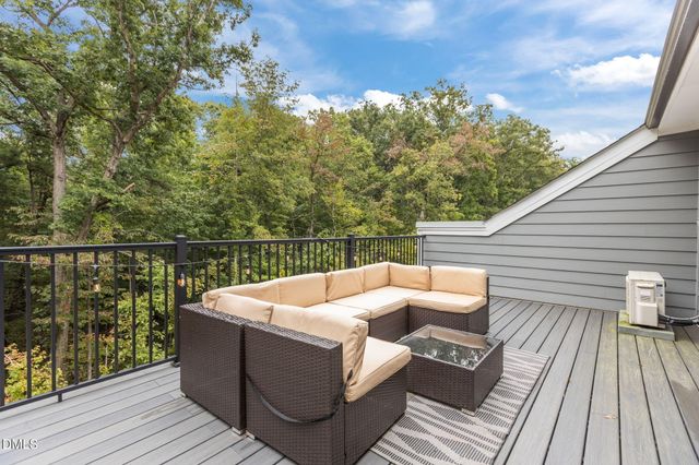 a balcony with table and chairs and potted plants