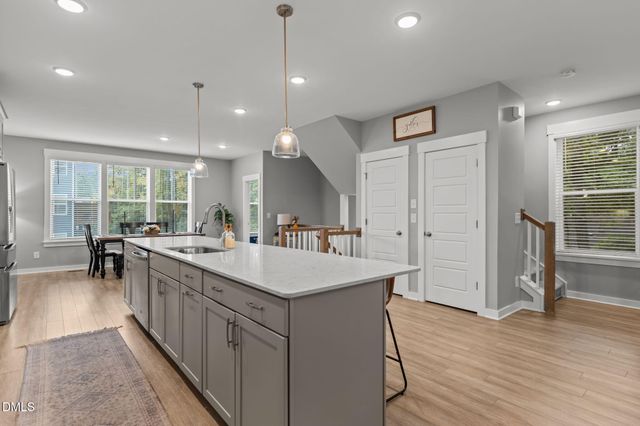 a kitchen with stainless steel appliances a stove a sink a refrigerator white cabinets and wooden floor