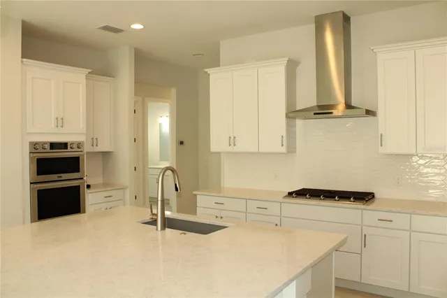 a kitchen with stainless steel appliances a stove a sink and white cabinets