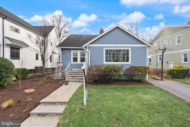 a view of a house with a big yard plants and large tree