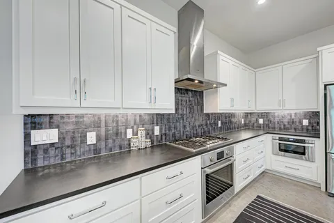 a kitchen with stainless steel appliances granite countertop a sink a stove and white cabinets
