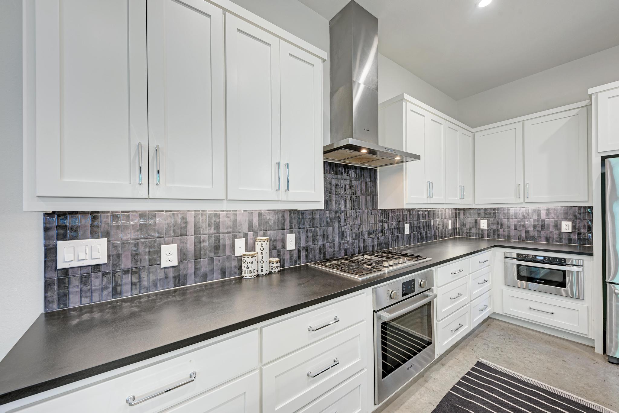 918 Cardinal Lane, Unit A Austin, TX 78704 - Photo 11 of 40 Built-in stainless appliances include a gas range with vent hood, microwave, and dishwasher.