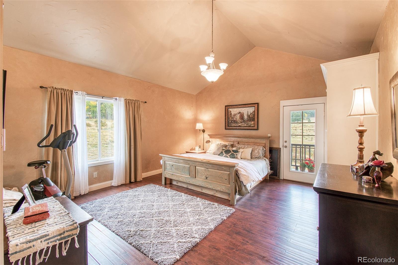 416 Conestoga Road Bailey, CO 80421 - Photo 16 of 40 a spacious bedroom with a bed and a dresser with wooden floor