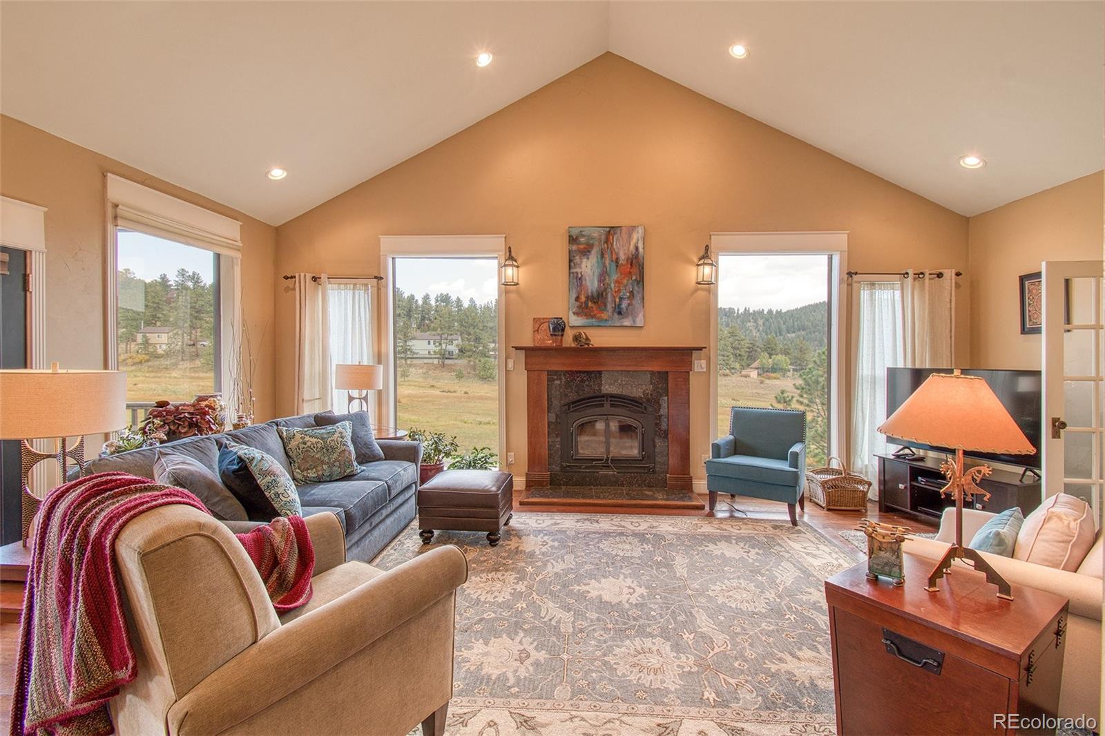 416 Conestoga Road Bailey, CO 80421 - Photo 8 of 40 a living room with furniture a fireplace and a floor to ceiling window