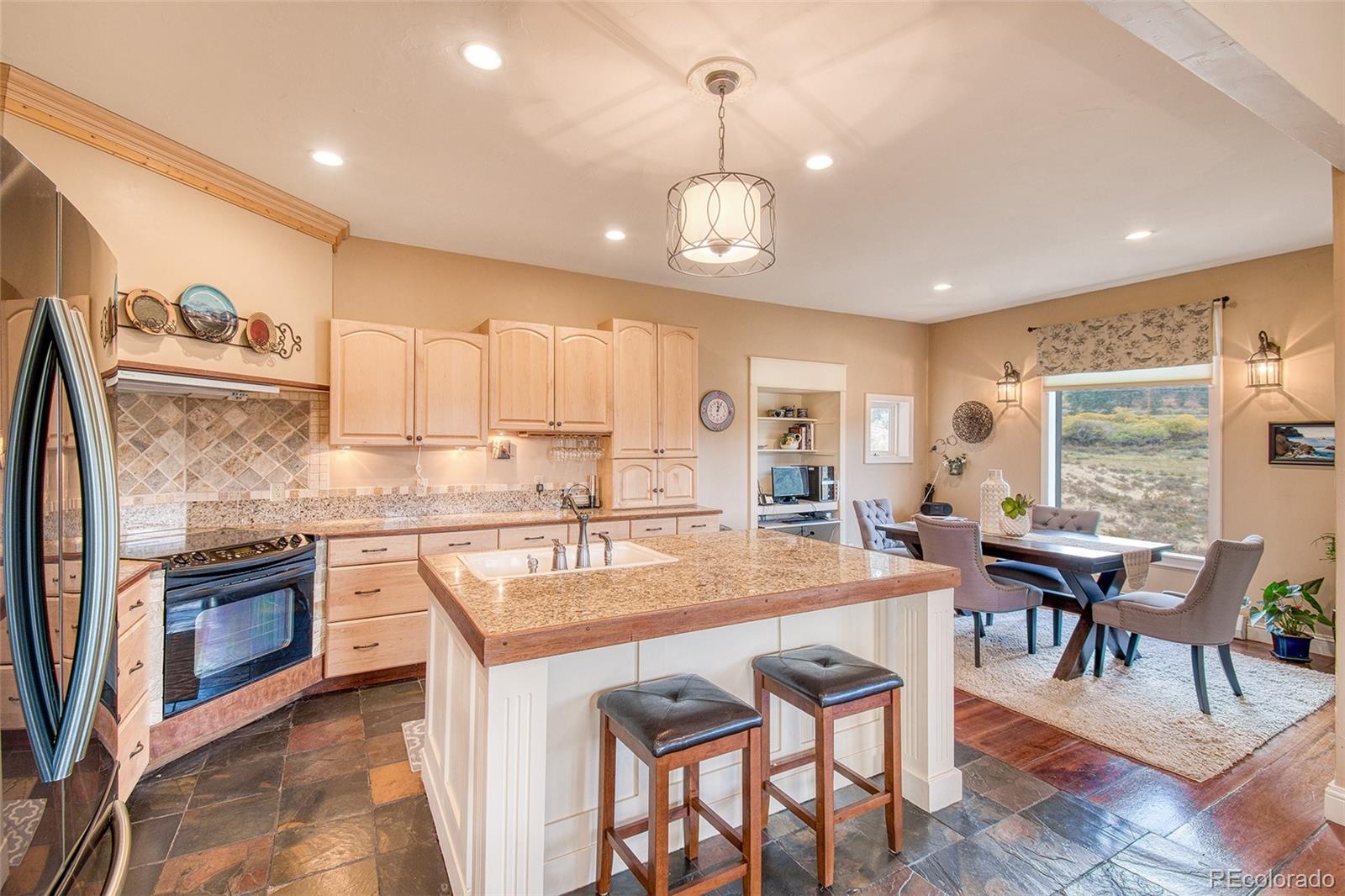 416 Conestoga Road Bailey, CO 80421 - Photo 10 of 40 a kitchen with stainless steel appliances granite countertop a stove top oven a sink dishwasher a dining table and chairs with wooden floor