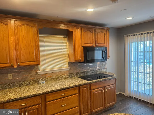a kitchen with granite countertop wooden cabinets a sink and a window