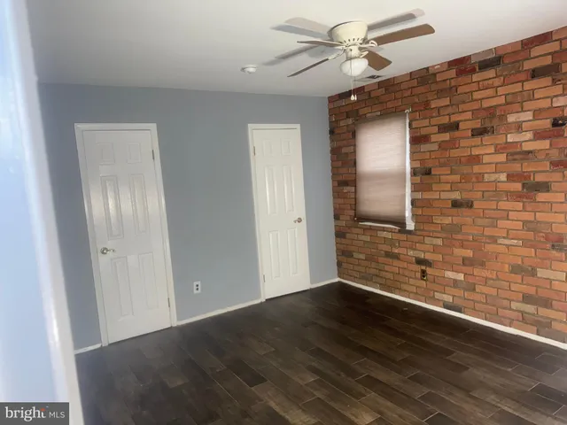a view of an empty room with wooden floor and fan