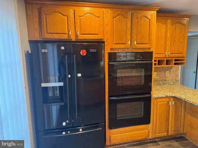 a kitchen with granite countertop wooden cabinets and a refrigerator