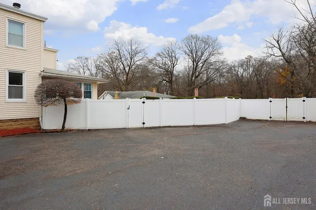 a view of a white house that has a large tree in front of it