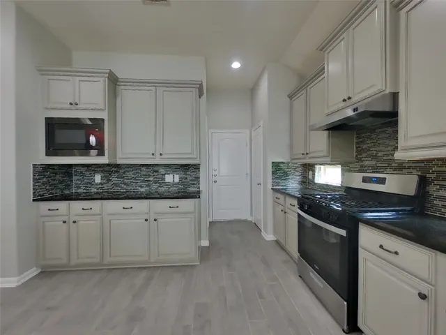 a kitchen with stainless steel appliances granite countertop a stove a sink and white cabinets