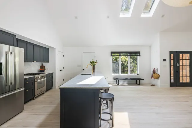 a kitchen with stainless steel appliances kitchen island granite countertop a sink a stove and refrigerator