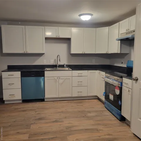 a view of a electric appliances in kitchen and empty room with wooden floor