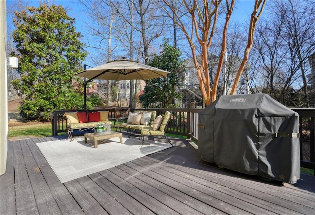 1260 Elk Ridge Cove Alpharetta, GA 30005 - Photo 55 of 87 a view of a deck with table and chairs under an umbrella with wooden floor and fence