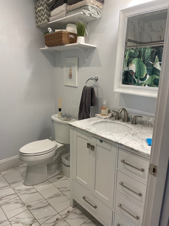 227 Bowen Street, Unit 3 Boston, MA 02127 - Photo 3 of 9 a bathroom with a granite countertop toilet a sink and a mirror