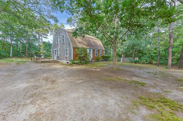 a view of a house with a yard and large trees