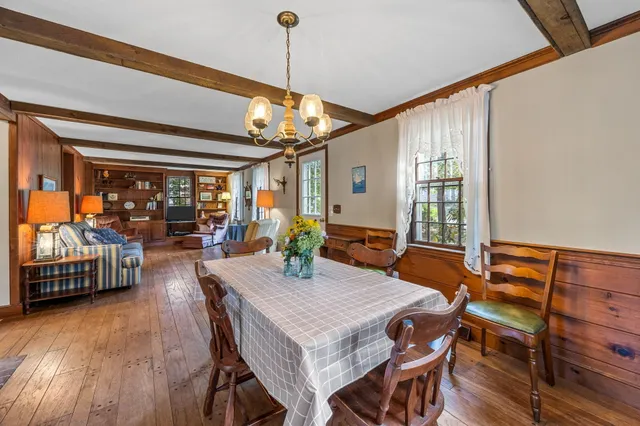 a view of a dining room and livingroom with furniture wooden floor a chandelier