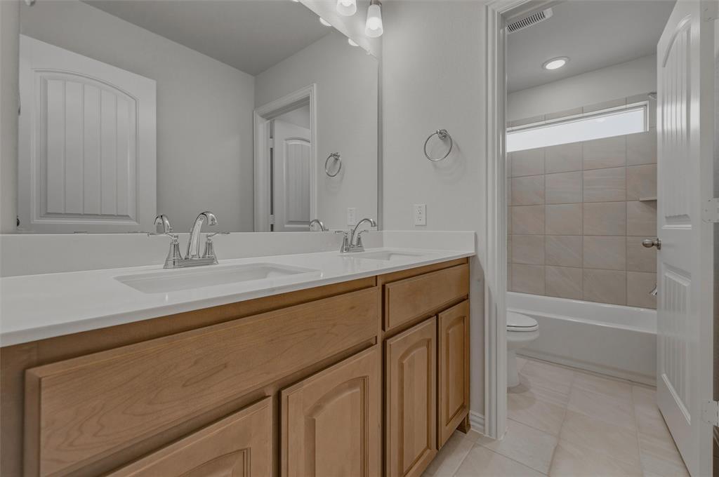 1337 Frio Drive Springtown, TX 76082 - Photo 32 of 40 Dual vanity with white undermount sinks, chrome fixtures, and wood cabinetry