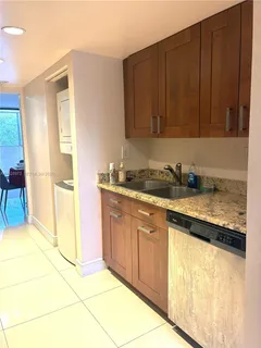 a kitchen with granite countertop a sink cabinets and stainless steel appliances