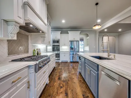 a kitchen with stainless steel appliances granite countertop a stove a refrigerator a sink dishwasher and a dining table with wooden floor