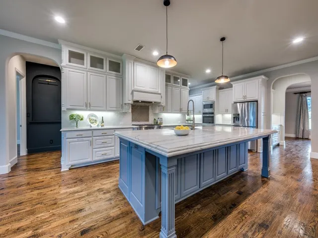 a kitchen with stainless steel appliances granite countertop a large kitchen island and a wooden floors