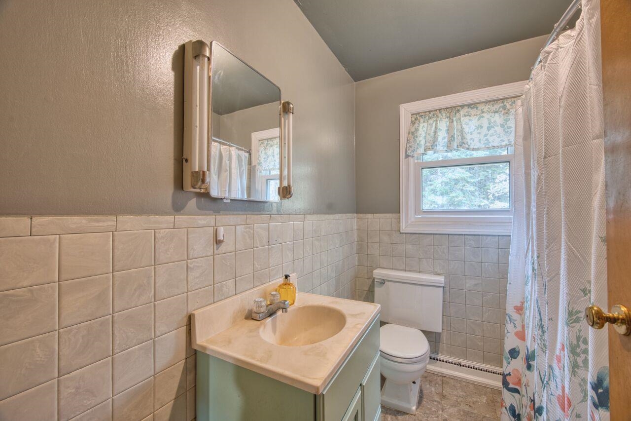 5462 Twin Lakes Loop 45 Aurora, MN 55705 - Photo 15 of 42 Bathroom featuring vanity, tile walls, a wainscoted wall, a textured wall, and a shower with shower curtain