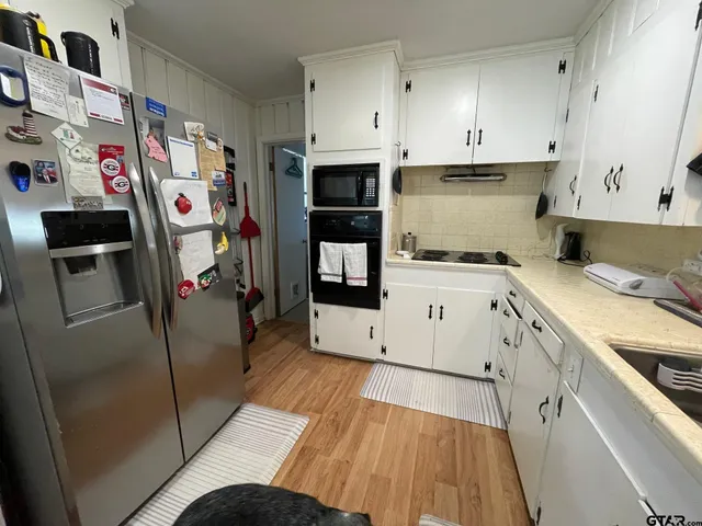a view of a kitchen with fridge and wooden floor