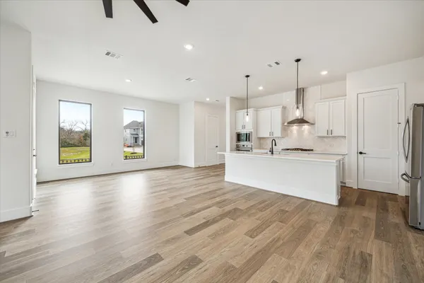 a large white kitchen with kitchen island a sink stainless steel appliances and cabinets