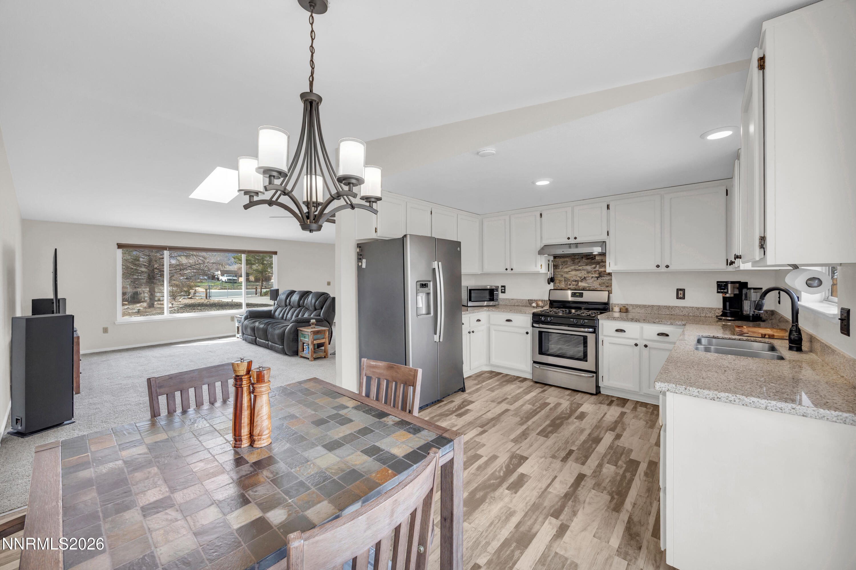 702 Ophir Court Dayton, NV 89403 - Photo 4 of 29 a kitchen with stainless steel appliances granite countertop a refrigerator a stove a sink a dining table and chairs with wooden floor