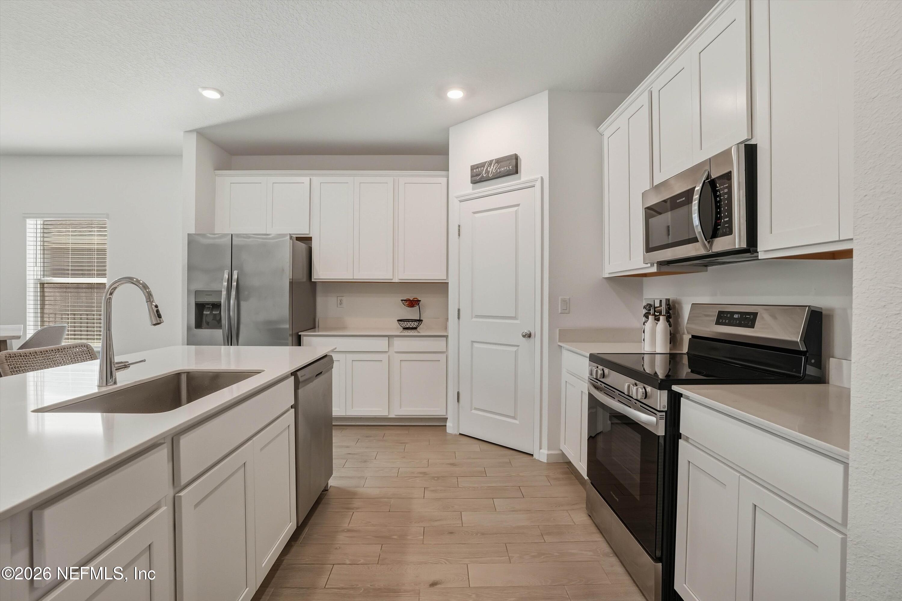 764 Lake Sinclair Street St. Augustine, FL 32084 - Photo 14 of 45 a kitchen with stainless steel appliances granite countertop white cabinets a sink a stove a microwave and a refrigerator