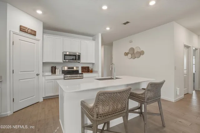 a kitchen with stainless steel appliances granite countertop white cabinets a sink a stove a microwave and a refrigerator