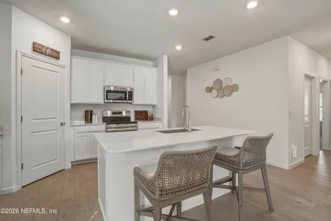 a kitchen with stainless steel appliances granite countertop white cabinets a sink a stove a microwave and a refrigerator