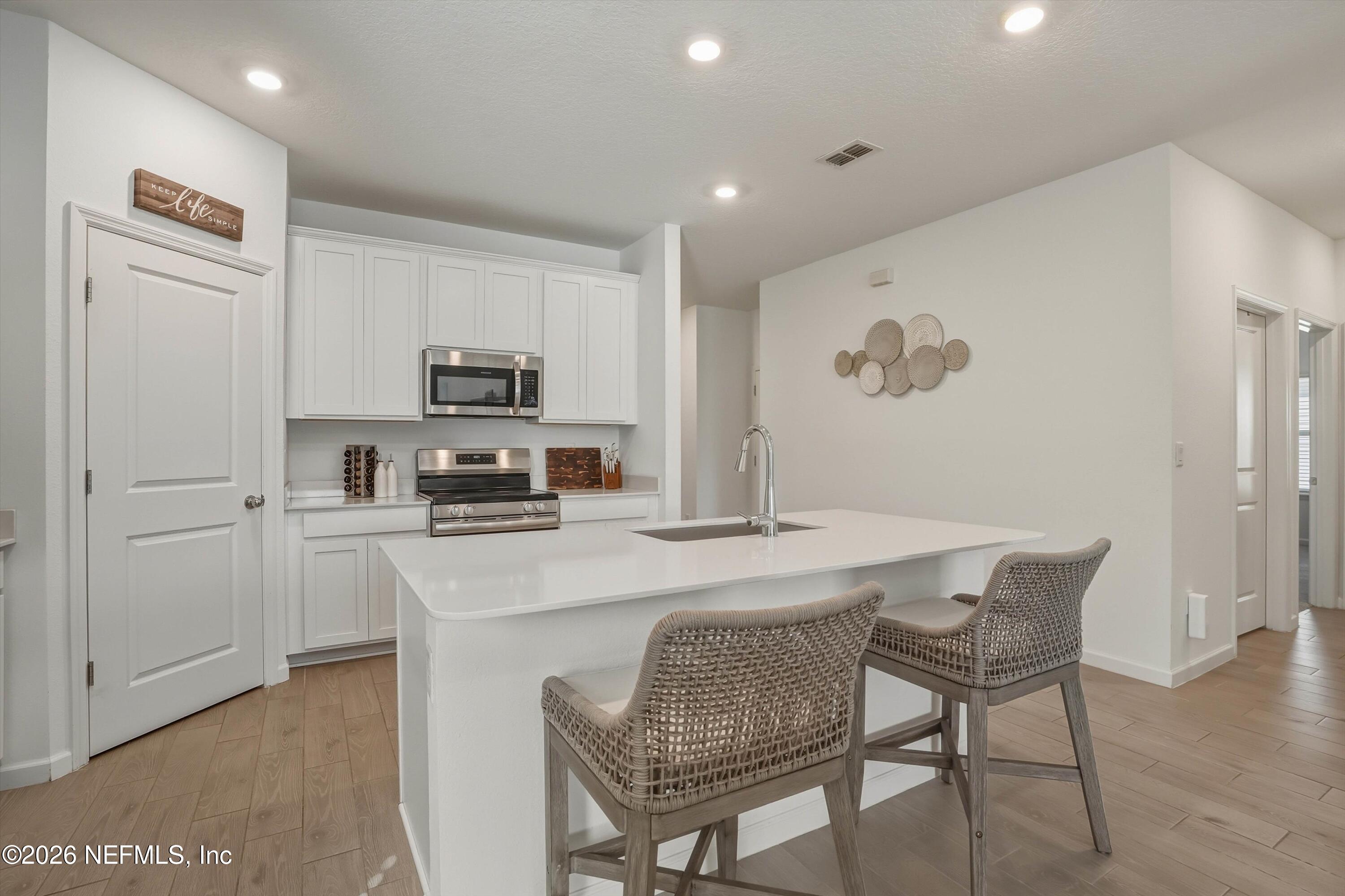 764 Lake Sinclair Street St. Augustine, FL 32084 - Photo 15 of 45 a kitchen with stainless steel appliances granite countertop a refrigerator a stove a sink a dining table and chairs